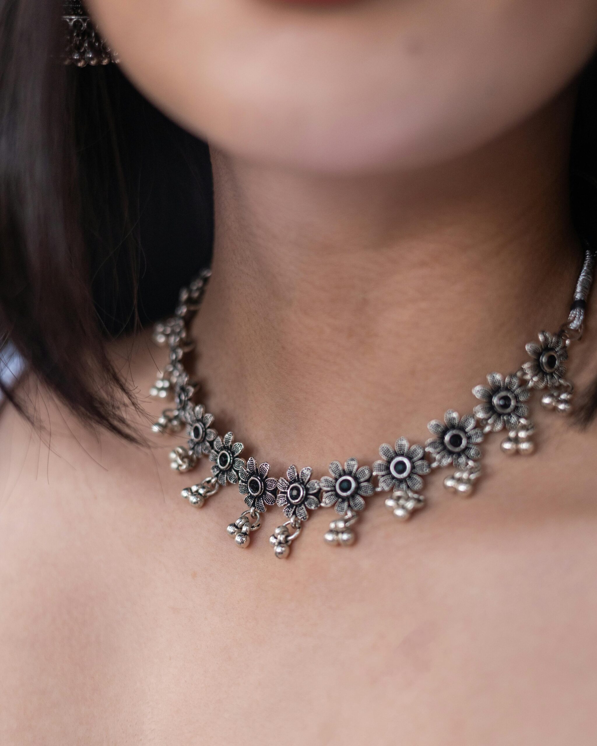 Close-up of an elegant floral silver choker necklace worn by a woman, highlighting intricate designs.